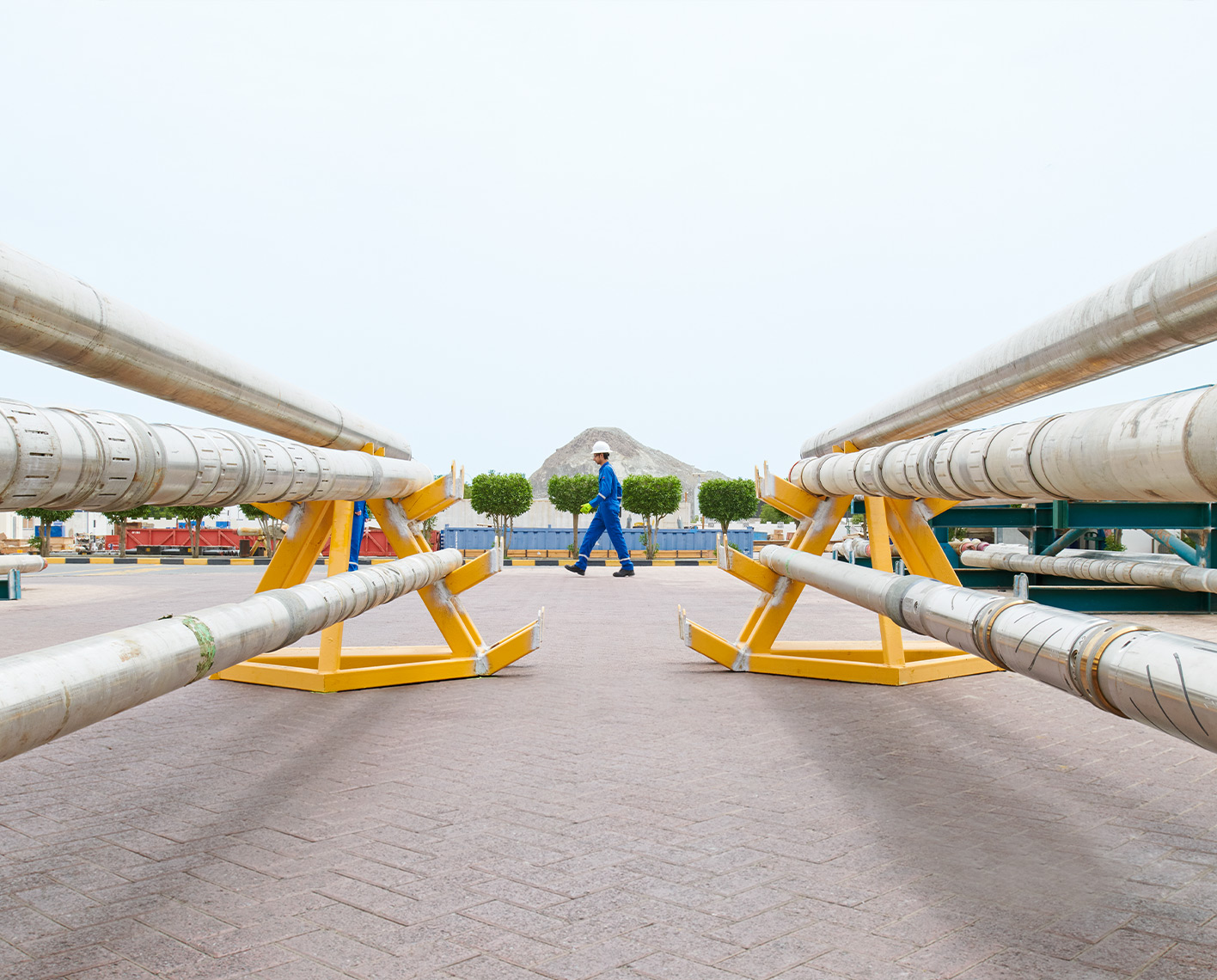 SLB engineer walking outside between two pipes laying down